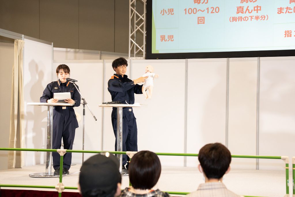 救命講習のステージで人形を使った応急手当の実演を行っている様子