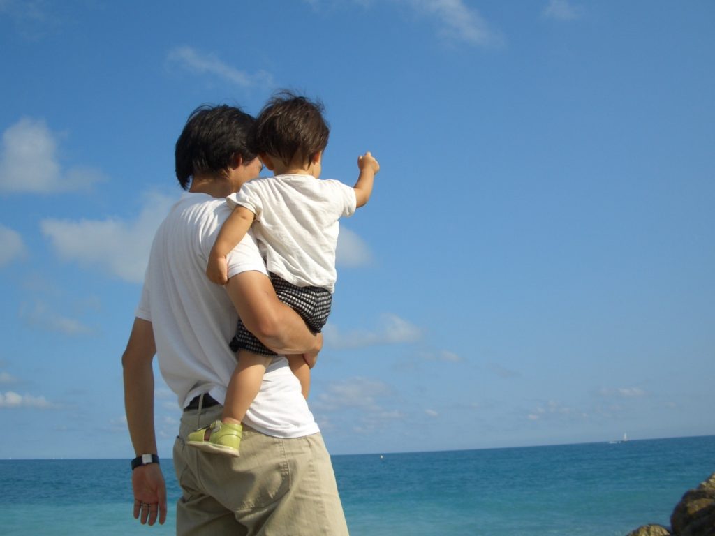 子供とお父さんが海を見ている写真
